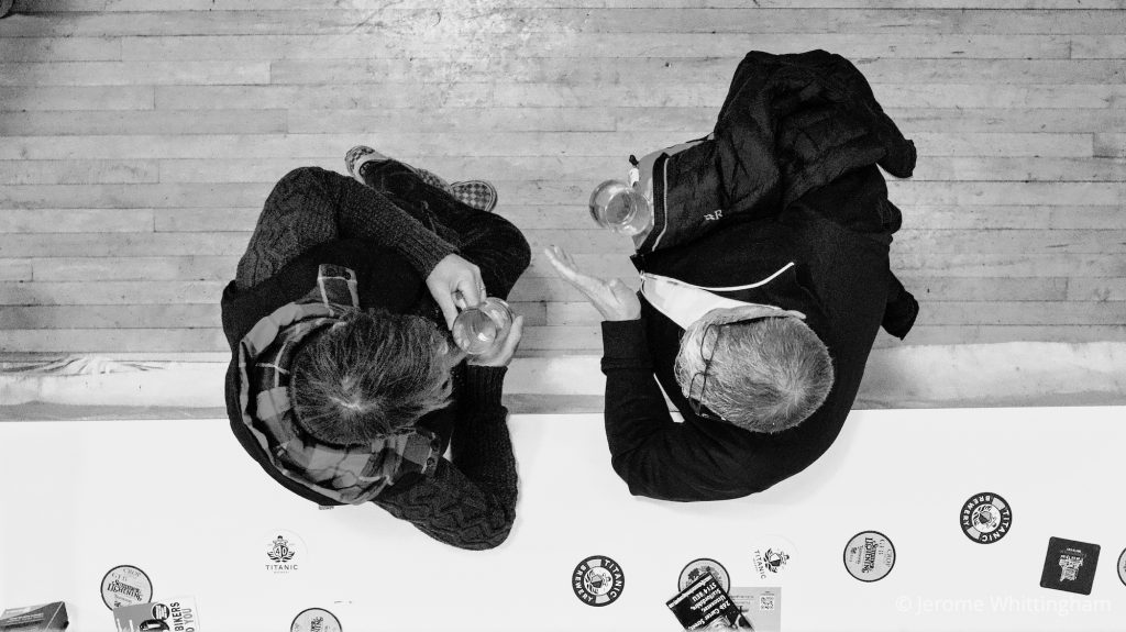 2 men sip beer and chat